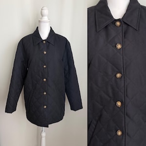 May include: Black quilted jacket with a button-up front and a classic collar. The jacket features a diamond pattern and is displayed on a white mannequin. The buttons are a light brown color. The jacket is a medium length.