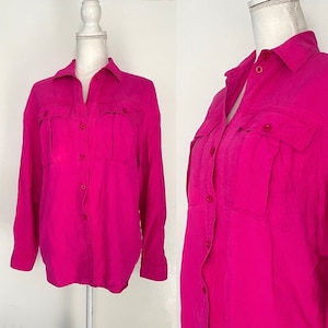 May include: A long-sleeved, button-up shirt in a bright pink color. The shirt has two large pockets on the front and a button-down collar.