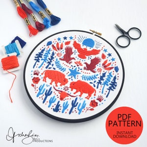 May include: Embroidered hoop art featuring a red, white and blue design with a sunset, stars, cacti, trees, and buffalo. The hoop is 8 inches in diameter and is perfect for adding a touch of rustic charm to your home decor.