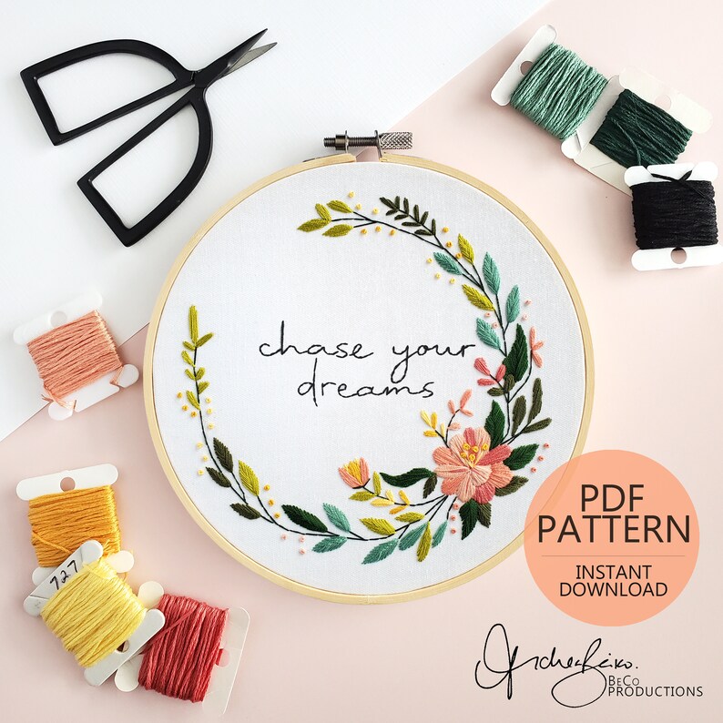 May include: Embroidery hoop with a floral wreath design and the text "chase your dreams". The hoop is surrounded by colorful embroidery floss spools.
