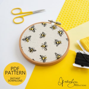 May include: A close-up of a white embroidery hoop with a pattern of black and yellow bees. The hoop is on a yellow background with a honeycomb pattern. The text "PDF PATTERN INSTANT DOWNLOAD" is in the lower left corner of the image.