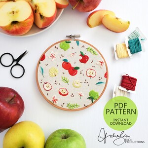 May include: A PDF pattern for an embroidery hoop featuring a red apple design. The hoop is surrounded by apples, scissors, and embroidery floss. The text "PDF PATTERN INSTANT DOWNLOAD" is visible in the image.
