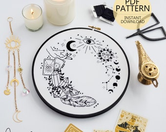 May include: An embroidery hoop with a black and white celestial design, featuring moons, stars, and crystals. The image includes candles, tarot cards, a gold-colored genie lamp, and a hanging sun and moon mobile. Text reads "PDF PATTERN INSTANT DOWNLOAD."