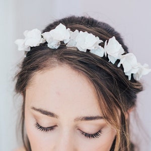 May include: A bride wearing a white strapless dress and a flower crown with a single pink rose in her hand.