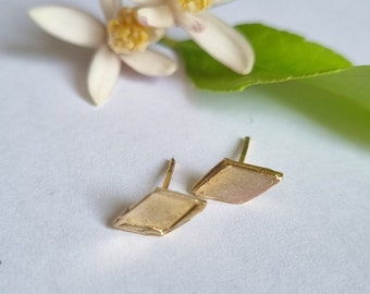 May include: A pair of gold-toned diamond-shaped earrings with a post back closure.