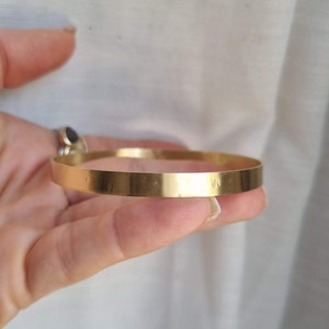 May include: A simple gold bangle bracelet with a smooth, polished finish.