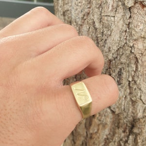 May include: A gold signet ring with the initials "WW" engraved on the top.