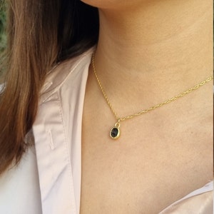 May include: A gold chain necklace with a small, round, black gemstone pendant.
