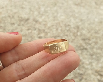 May include: A gold signet ring with the letter "N" engraved on the top.