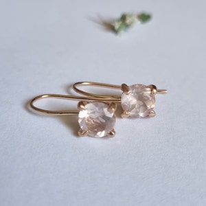 May include: A pair of rose gold earrings with a light pink gemstone in each earring.
