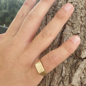 May include: A gold signet ring with the initials "A.B." engraved on the top.