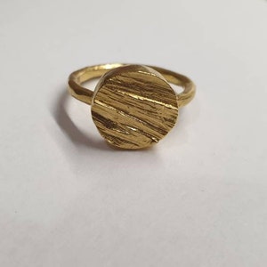 May include: A gold ring with a textured, circular band.