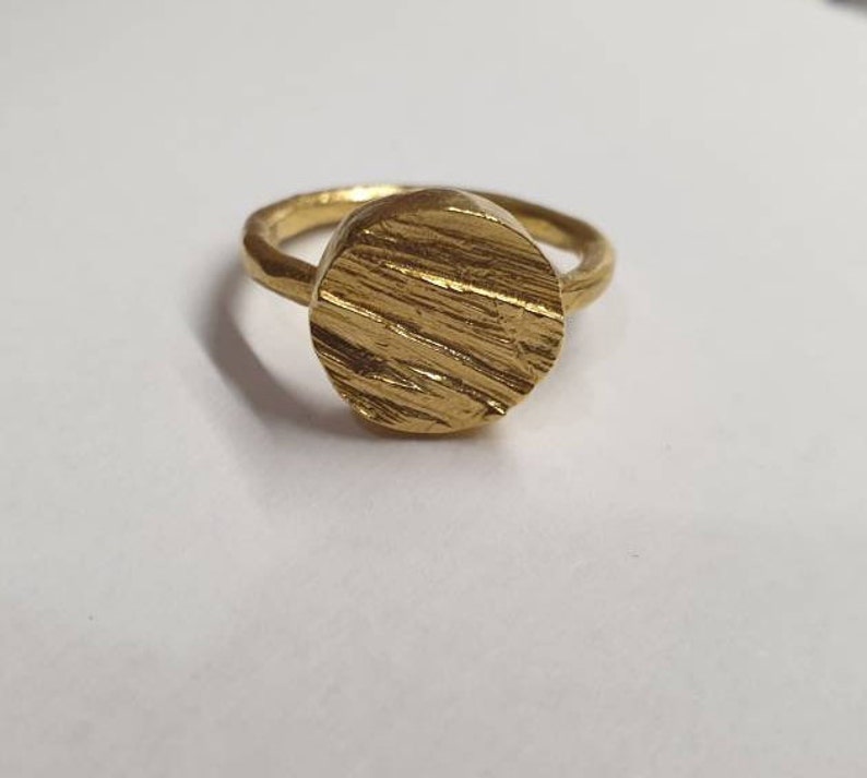 May include: A gold ring with a textured, circular band.