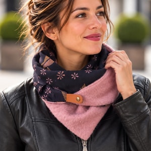 Peut inclure: Une écharpe infinie bicolore composée d'un tissu bleu marine foncé à petits motifs floraux roses d'un côté et d'un tissu texturé rose poudré uni de l'autre. L'écharpe est fixée par une patte en cuir beige et un bouton-pression doré.
