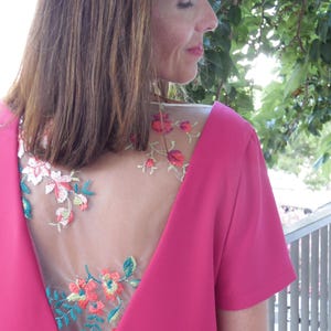 Pu&ograve; includere: Un abito rosa con un pannello posteriore trasparente con ricamo floreale. Il ricamo &egrave; in tonalit&agrave; di rosso, arancione, verde e giallo.