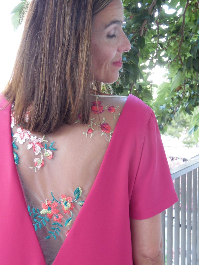 Pu&ograve; includere: Un abito rosa con un pannello posteriore trasparente con ricamo floreale. Il ricamo &egrave; in tonalit&agrave; di rosso, arancione, verde e giallo.