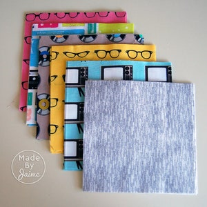 May include: Stack of fabric squares with various retro patterns, including records, eyeglasses, televisions, and a grey textured fabric square.