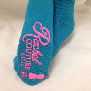 May include: A pair of turquoise blue ankle socks with pink embroidery that reads "Rachel Couture 10.17.15".