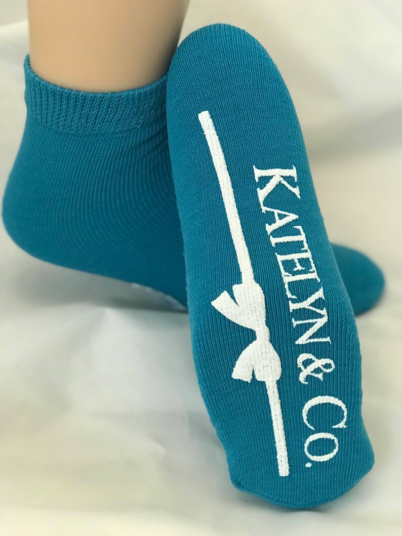 May include: Teal blue ankle socks with a white bow and the text "Katelyn & Co." printed on the heel.