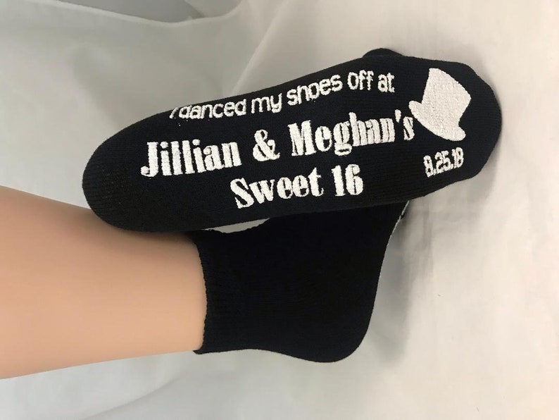 Puede incluir: Calcetines negros con texto blanco que dice "I danced my shoes off at Jillian & Meghan's Sweet 16 8.25.18" y un peque&ntilde;o gr&aacute;fico de sombrero de copa.