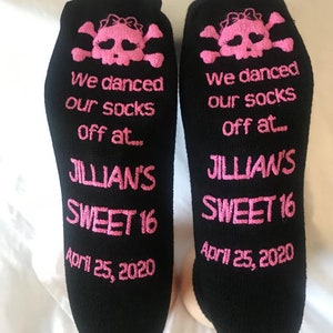 Puede incluir: Un par de calcetines negros con dise&ntilde;os de calaveras y huesos cruzados rosas. Los calcetines tienen el texto "We danced our socks off at... Jillian's Sweet 16 April 25, 2020".