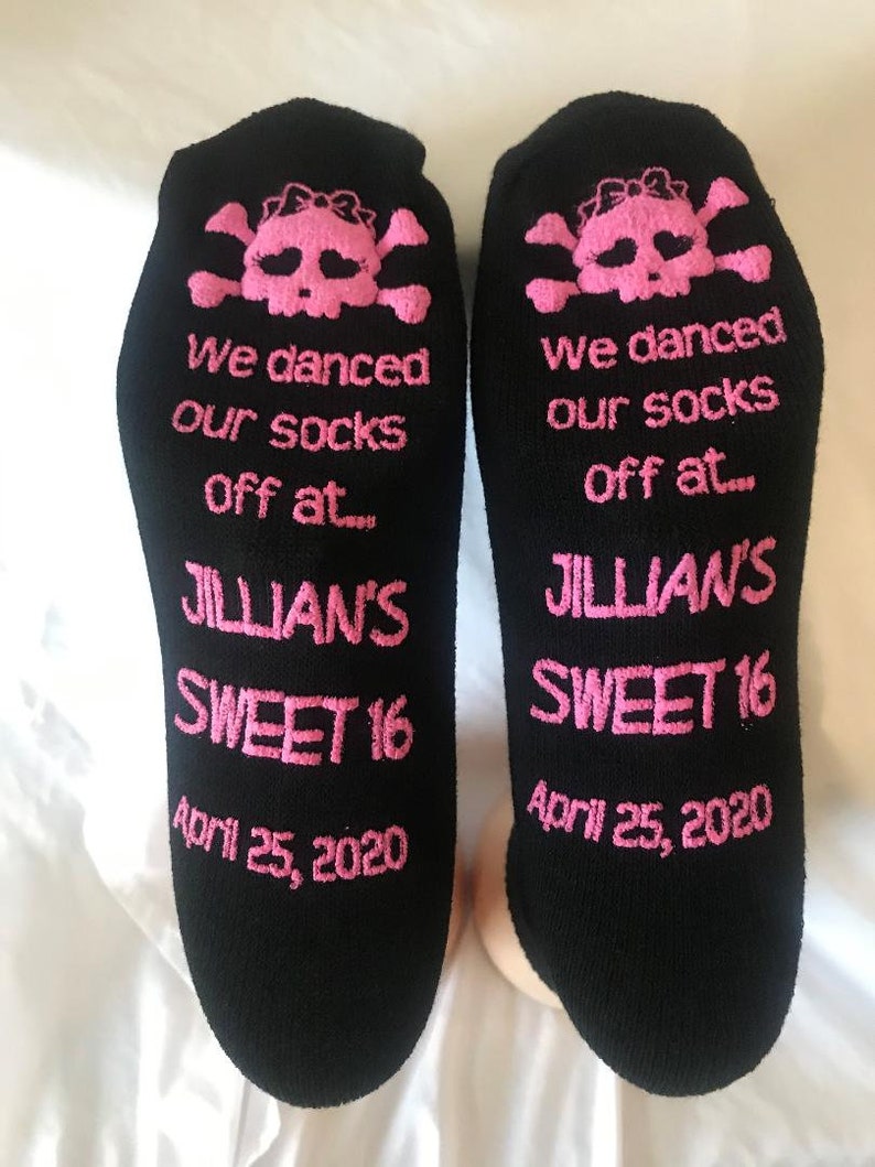 Puede incluir: Un par de calcetines negros con dise&ntilde;os de calaveras y huesos cruzados rosas. Los calcetines tienen el texto "We danced our socks off at... Jillian's Sweet 16 April 25, 2020".