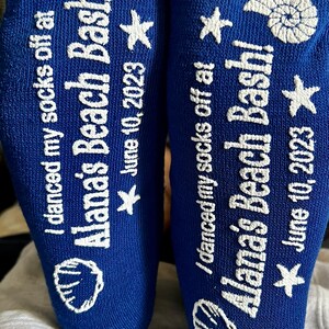 May include: A pair of blue socks with white text that reads "I danced my socks off at Alana's Beach Bash! June 10, 2023". The socks have a seashell and star design.