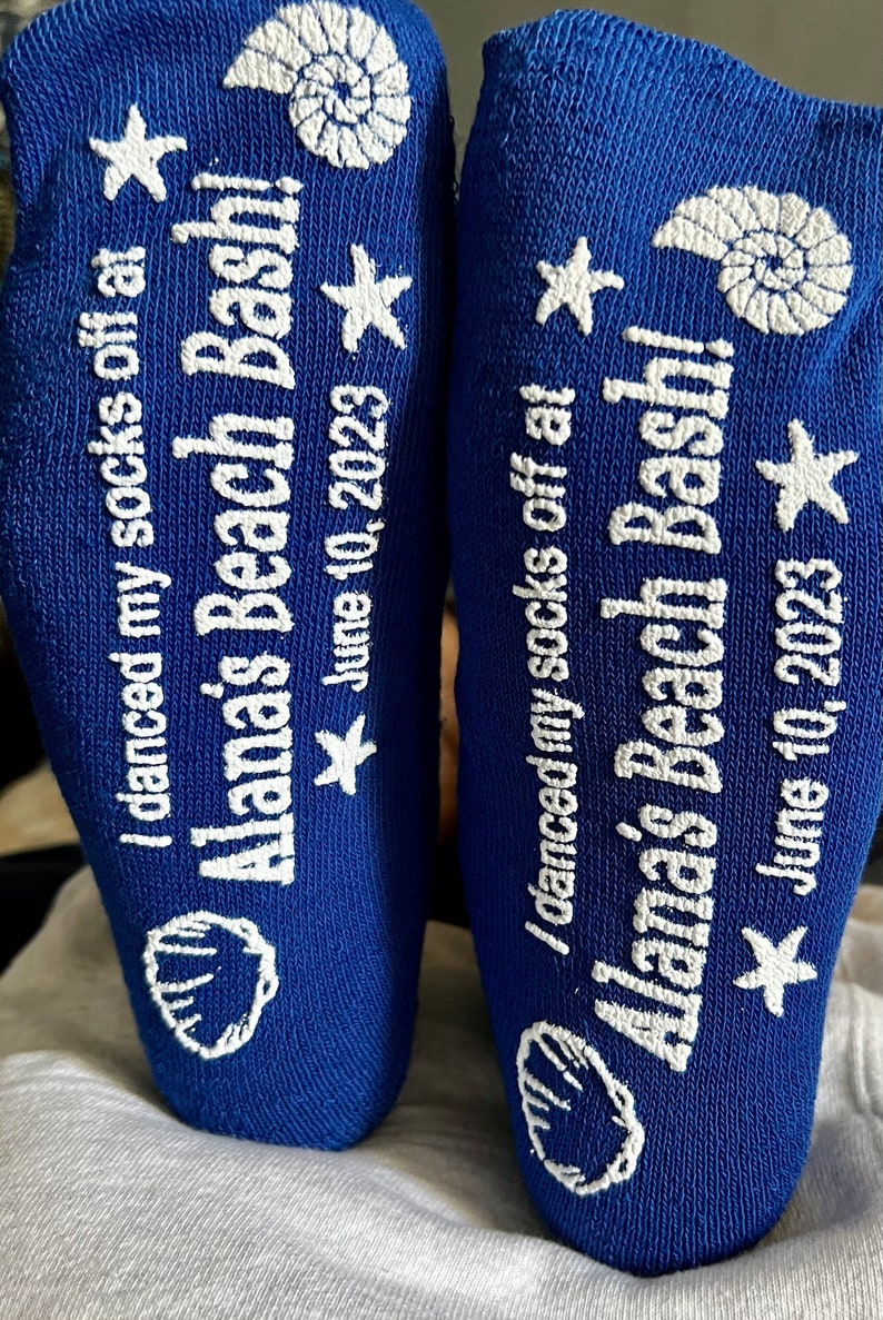 May include: A pair of blue socks with white text that reads "I danced my socks off at Alana's Beach Bash! June 10, 2023". The socks have a seashell and star design.