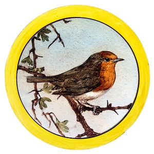 May include: A robin perched on a branch with green leaves, painted on a white ceramic plate with a yellow border.