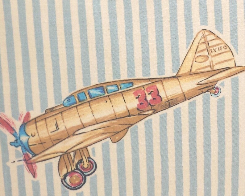 May include: A vintage-style illustration of a brown airplane with a red number 33 on the side. The airplane is flying over a blue and white striped background. The airplane has a blue propeller and a white tail with the text "IK 170" on it.