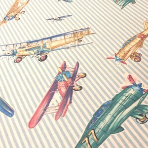 May include: A blue and white striped background with various vintage airplanes in different colors and designs. The airplanes are in various positions, some flying, some landing, and some in mid-air.