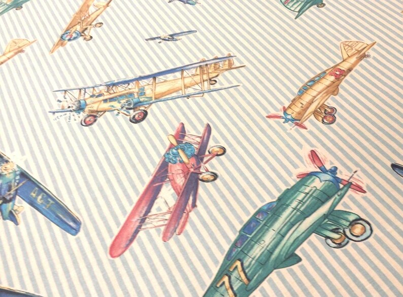 May include: A blue and white striped background with various vintage airplanes in different colors and designs. The airplanes are in various positions, some flying, some landing, and some in mid-air.