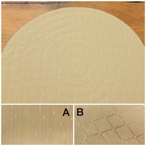 May include: A round, beige placemat with a concentric circle pattern. The placemat has a subtle, textured surface with small white dots.