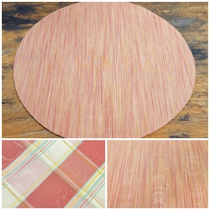 May include: A round, woven placemat with a red and beige striped pattern. The placemat is made of natural fibers and has a slightly textured surface.