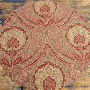 May include: A round, red and gold patterned placemat with a paisley design.