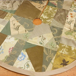 May include: A circular patchwork tree skirt with a beige border. The skirt is made of various fabrics in shades of green, brown, and beige, with floral and paisley patterns.
