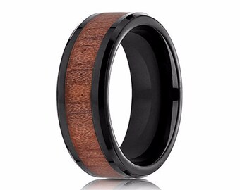 Op de afbeelding: Een zwarte keramische ring met een bruine houten inlay. De ring heeft een afgeschuinde rand en een gepolijste afwerking.