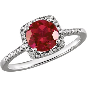 May include: A silver ring with a red gemstone surrounded by a halo of smaller diamonds. The ring has a square-shaped setting and a band that is set with smaller diamonds.