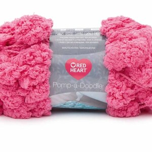 May include: A pink ball of yarn labeled "Pomp-a-Doodle" by Red Heart. The yarn is made of 100% polyester.