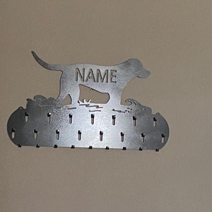 May include: Metal dog silhouette medal holder with the word "NAME" engraved on the dog's body. The holder has 20 hooks for hanging medals.