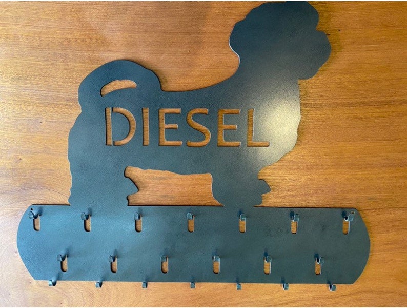 May include: Metal key holder shaped like a dog silhouette with the name "Diesel" cut out. The holder has 15 hooks for hanging keys.