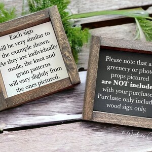 May include: Two wooden signs with black text on a white background. The sign on the left says "Each sign will be very similar to the example shown. As they are individually made, the knot and grain patterns will vary slightly from the ones pictured." The sign on the right says "Please note that any greenery or photo props pictured are NOT included with your purchase. Purchase only includes wood sign only."