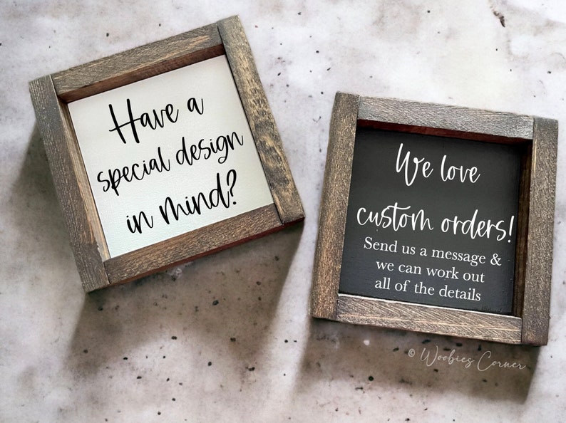 May include: Two wooden signs with a rustic finish. The sign on the left says "Have a special design in mind?" The sign on the right says "We love custom orders! Send us a message & we can work out all of the details." The signs are on a gray background.