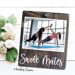 May include: A brown wooden sign with a photo of two women doing a plank exercise. The sign says "Swole Mates" and "Woobies Corner" in white lettering.