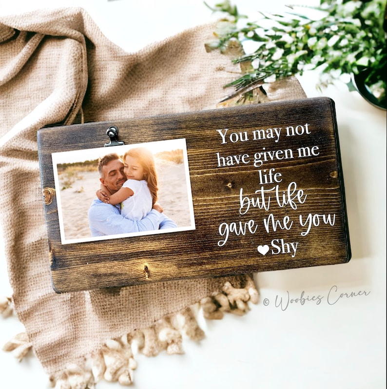 May include: A wooden photo frame with a clip to hold a photo. The frame has a white inscription that reads "You may not have given me life but life gave me you Shy".