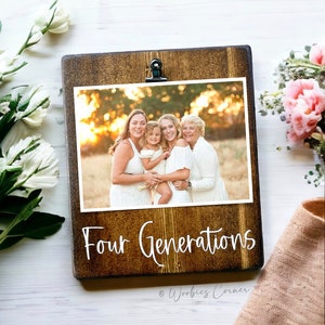 May include: A wooden photo frame with a brown stain and a black clip. The frame holds a photo of four generations of a family. The text "Four Generations" is written in white on the frame. The text "Woobies Corner" is written in white at the bottom of the frame.