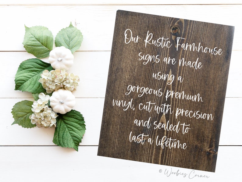 May include: A dark brown wooden sign with white text that reads "Our Rustic Farmhouse Signs are made using a gorgeous premium vinyl, cut with precision and sealed to last a lifetime." The sign is on a white wood background.