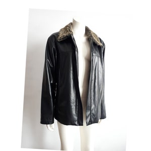May include: A black faux leather jacket with a brown faux fur collar. The jacket has a zip fastening and two pockets.