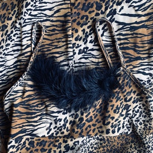 May include: A black and brown animal print halter top with a black feather trim. The top has a halter style with adjustable straps.