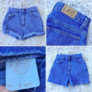 May include: Light blue denim shorts with a high waist and rolled cuffs. The shorts feature a classic five-pocket design and a Lee brand patch. The shorts are size 8 Med. Made in the USA.